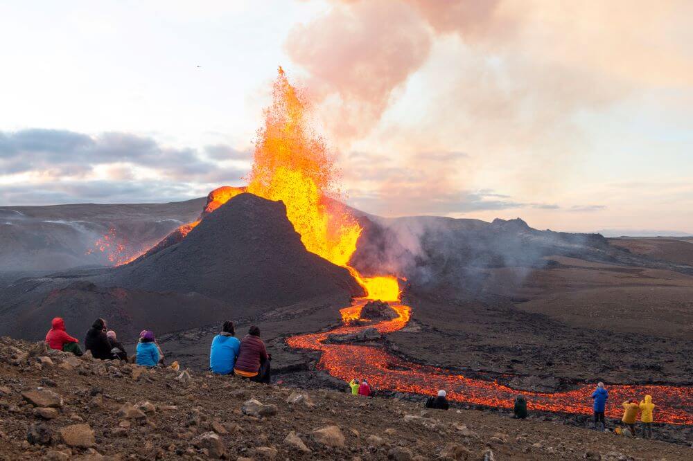 people watching volcano eruption at meradalir iceland.