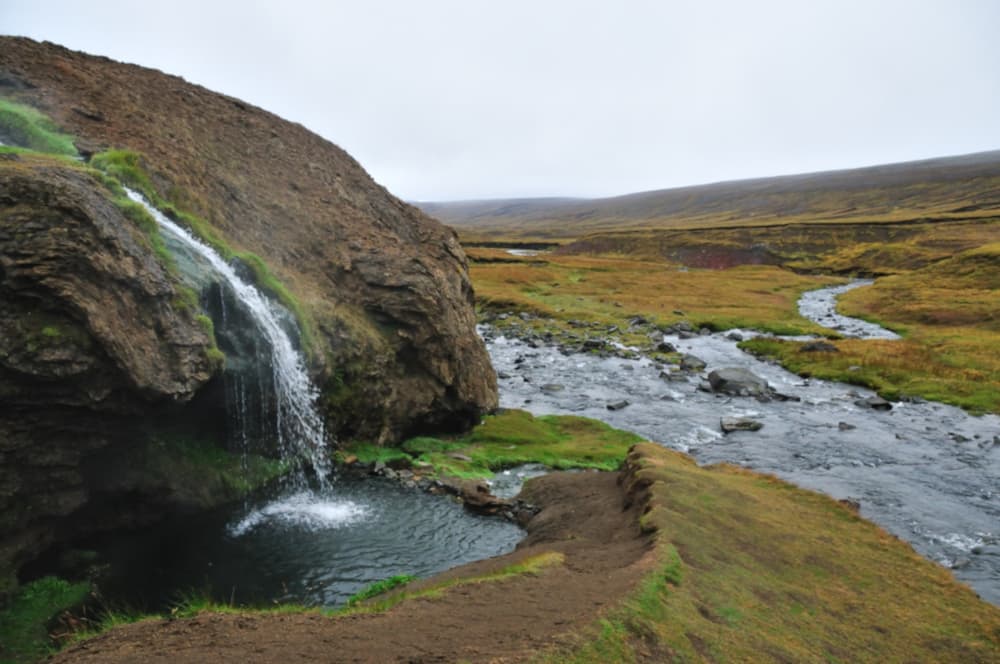 Waterfall feeding a natural pool. A small waterfall pouring into a natural pool beside a river in Iceland