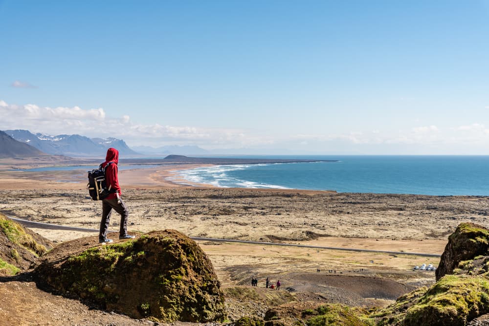 Rauðfeldsgjá Gorge (Snæfellsnes Peninsula Hiker standing atop a cliff with panoramic views of Iceland’s rugged coastline and wide open landscapes.