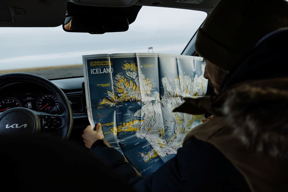 Hombre leyendo un mapa de Islandia dentro de un coche de alquiler.