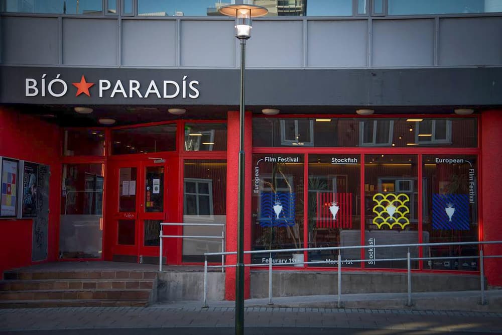 Entrance to Bíó Paradís cinema. Red storefront of Bíó Paradís cinema with festival banners in the windows