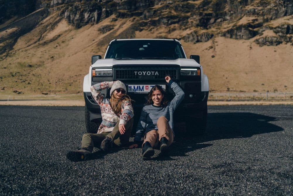 Sitting in Iceland. Two women sitting in front of a Toyota Land Cruiser in Iceland.