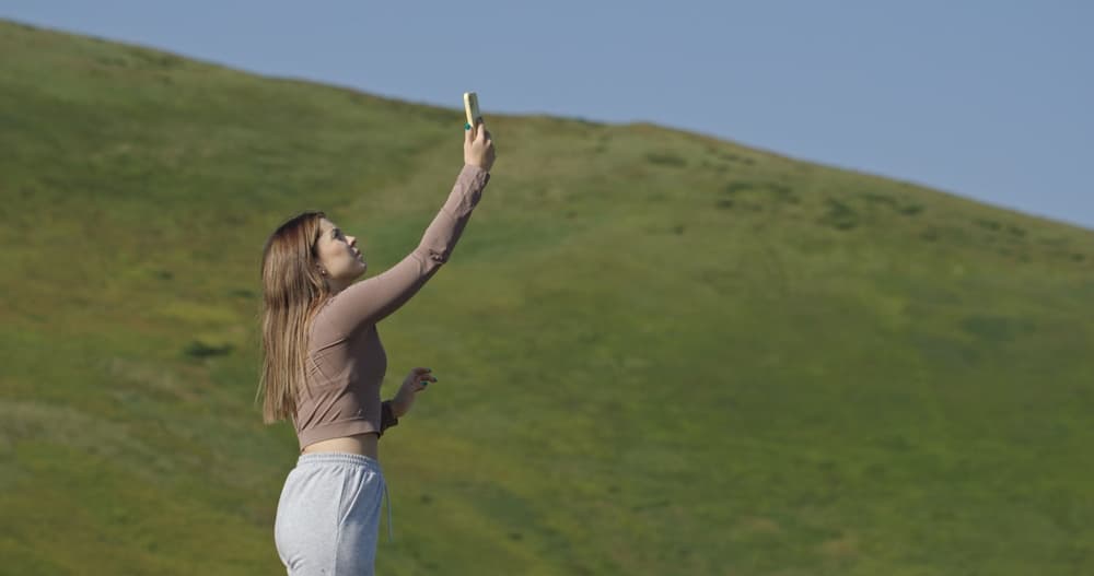 Auf der Suche nach Mobilfunkverbindung. Frau hält ihr Telefon in die Luft und sucht nach einer Mobilfunkverbindung.