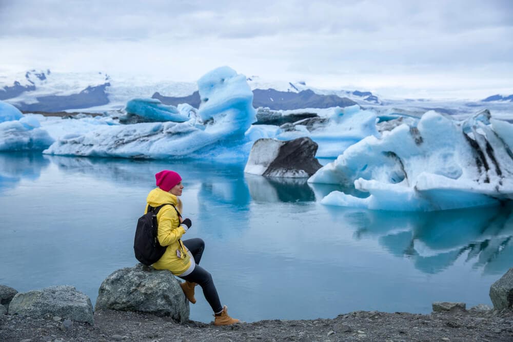 Person in yellow jacket at Jokulsarlon glacier lagoon in south Iceland.