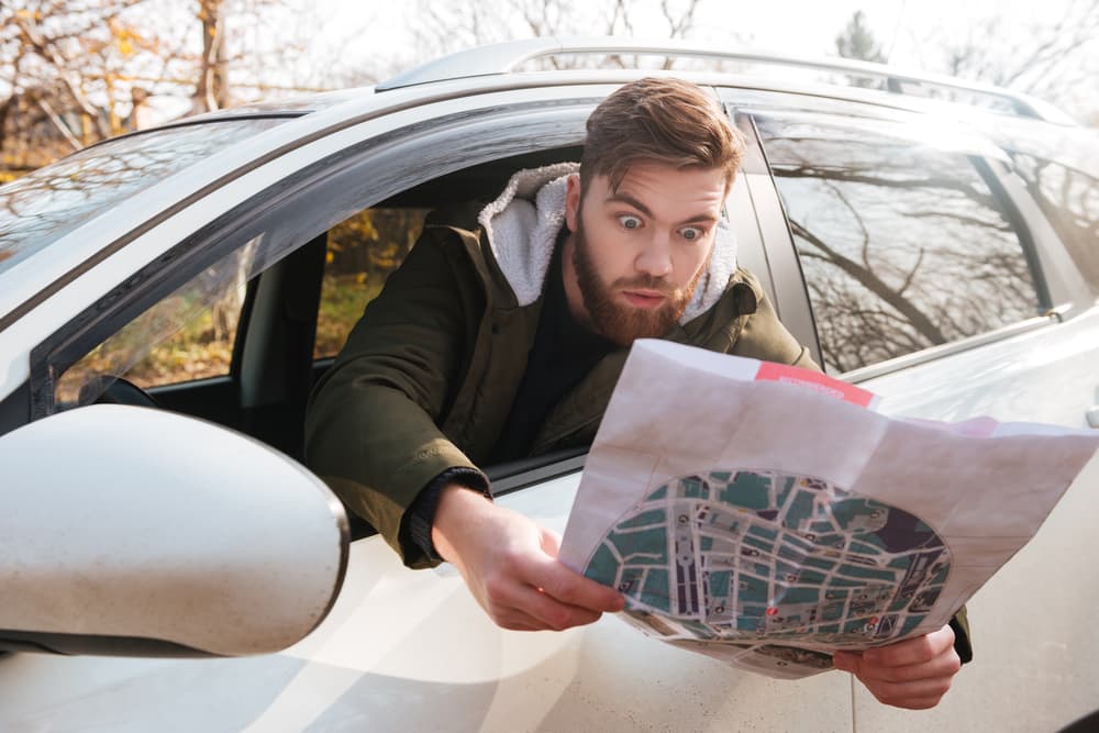 Be prepared in Iceland. Man looking at a map in a rental car.