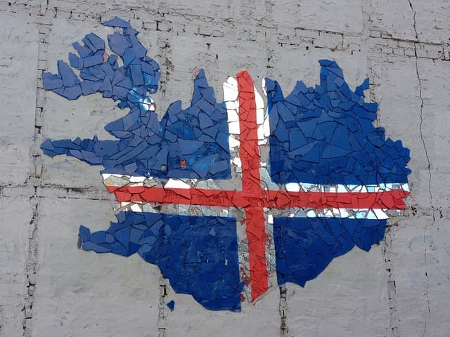 Flag mosaic on weathered wall. Mosaic mural of a flag shaped like an island on a cracked wall