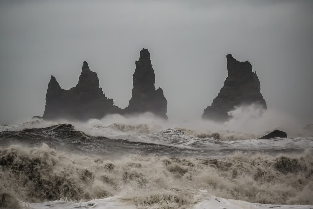 Clima costero extremo en Reynisdrangar Olas agitadas golpeando las formaciones marinas de Reynisdrangar bajo un cielo tormentoso cerca de Vík, Islandia.
