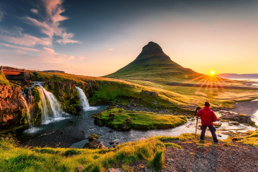 Man taking a photo at Kirkjufellsfoss in the midnigth sun. 