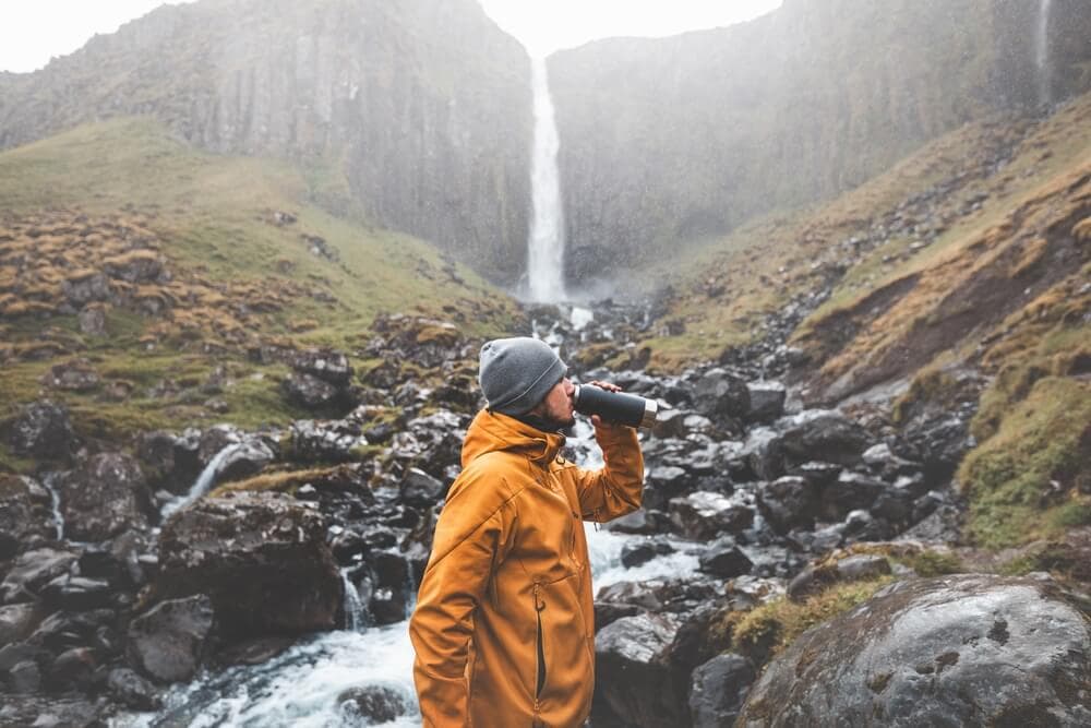 Man drinking from a stream in Iceland.