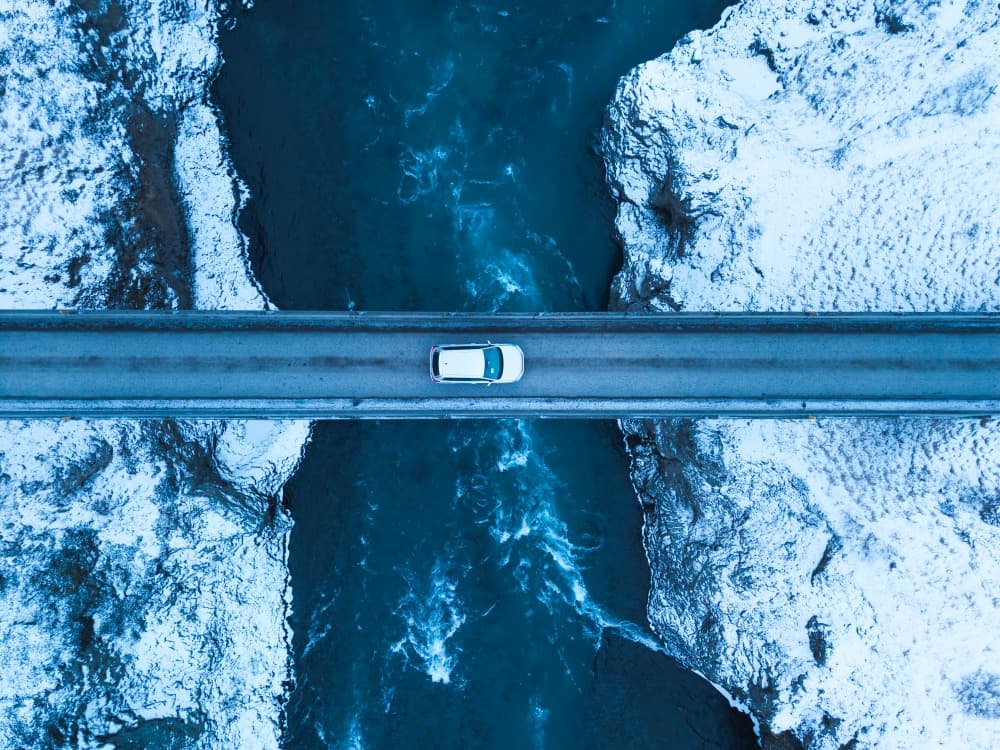 Río islandés en invierno. Coche blanco cruzando un puente en Islandia durante el invierno.