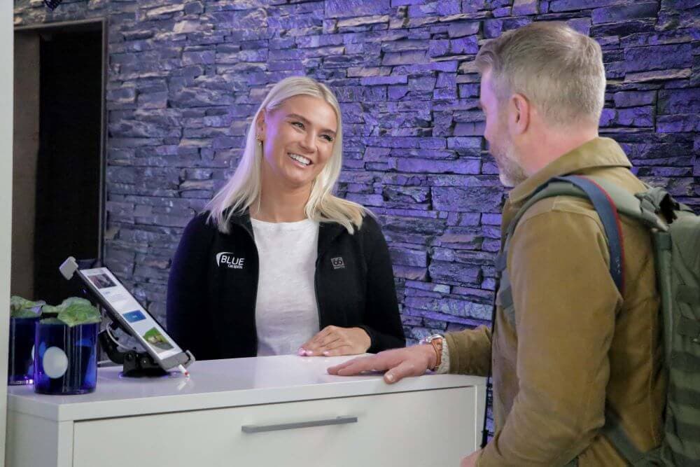 Blue car rental staff assisting a customer at kef airport office