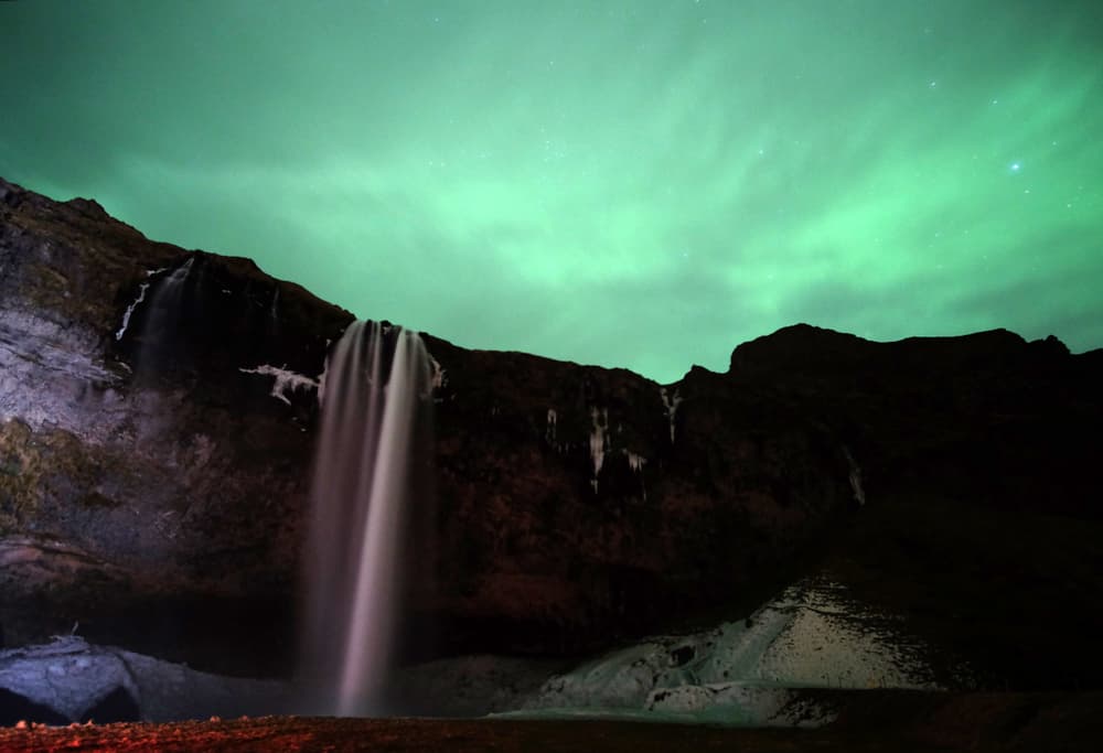 Nordlichter leuchten über dem Wasserfall Seljalandsfoss in Island.