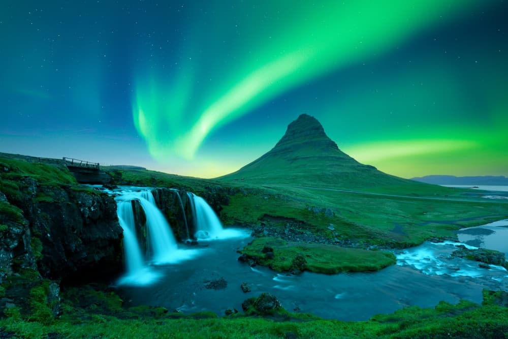 Der Berg und Wasserfall Kirkjufell unter den Nordlichtern auf der Halbinsel Snæfellsnes.