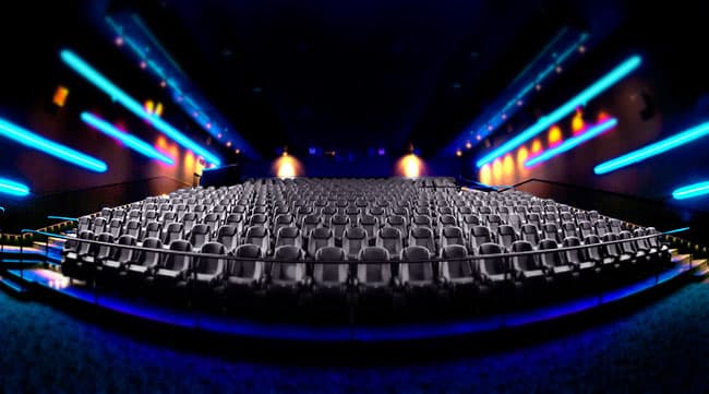 Inside an empty cinema hall. Empty cinema auditorium with rows of seats lit by blue neon lighting