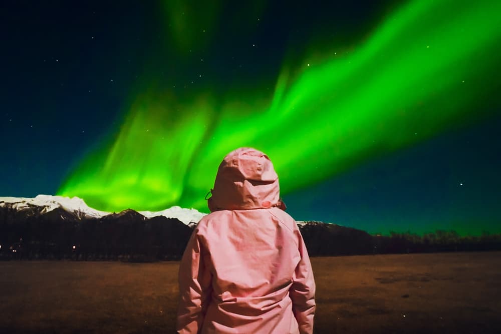 Women in pink and Northern lights in Iceland.