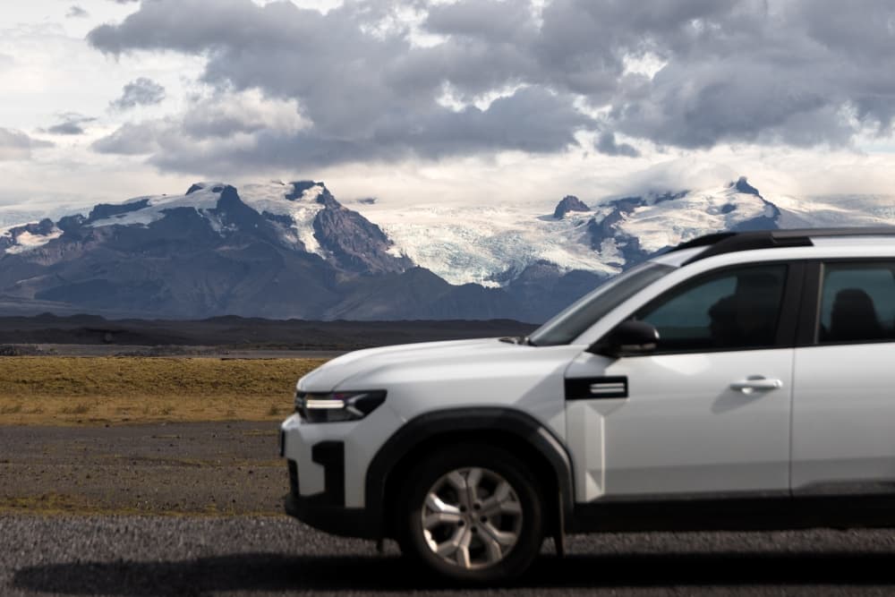 Car rental in Iceland. Withe 4x4 rental in Iceland road with mountains.