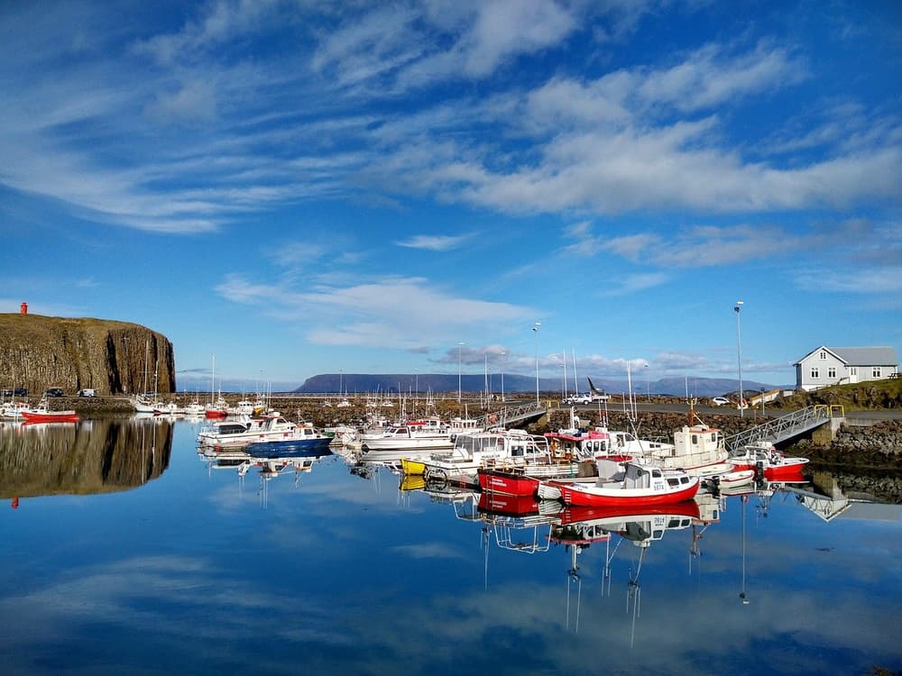 Boats docked in Stykkishólmur. Fishing boats moored in the calm harbour at Stykkishólmur under a blue sky