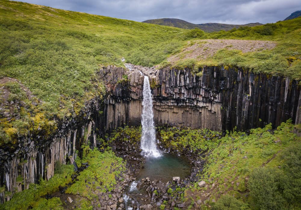 Photo en pose longue de la chute d'eau Svartifoss et de ses colonnes de basalte noir en Islande. Photo en pose longue de Svartifoss