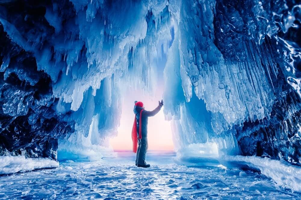 Man standing in a blue ice cave inside a glacier in Iceland.