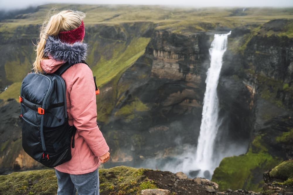 Iceland waterfall outwear. Women standing next to a waterfall in Iceland.