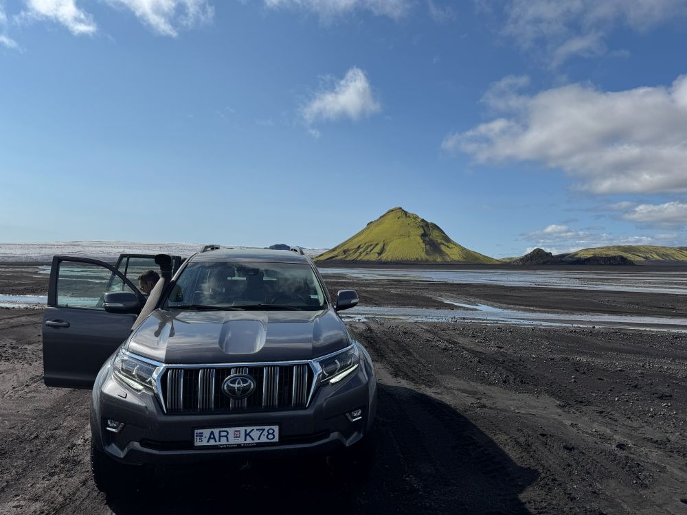Blue rental car in Icelandic landscape Rental car at an open viewpoint in Iceland during a summer road trip