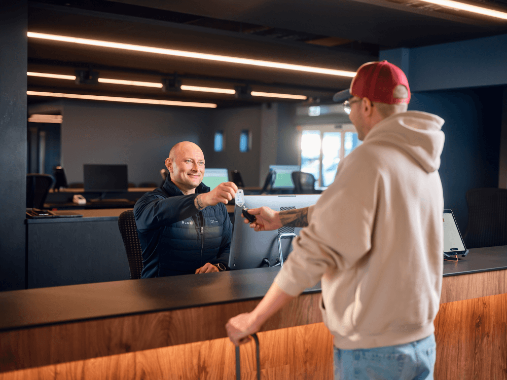 Blue car rental customer getting a key at Kef ariport office in Iceland.