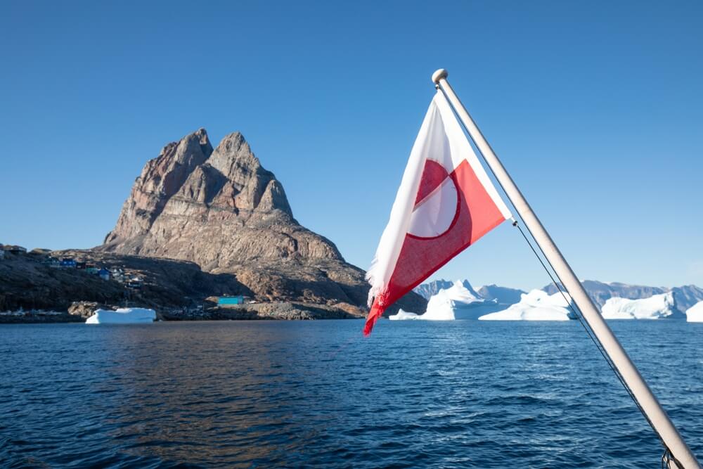 Greenland flag and icebergs seeing from a boat in Greenland.