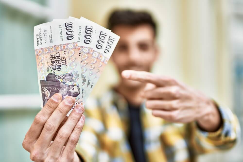 Hombre sosteniendo billetes de 1000 coronas islandesas.
