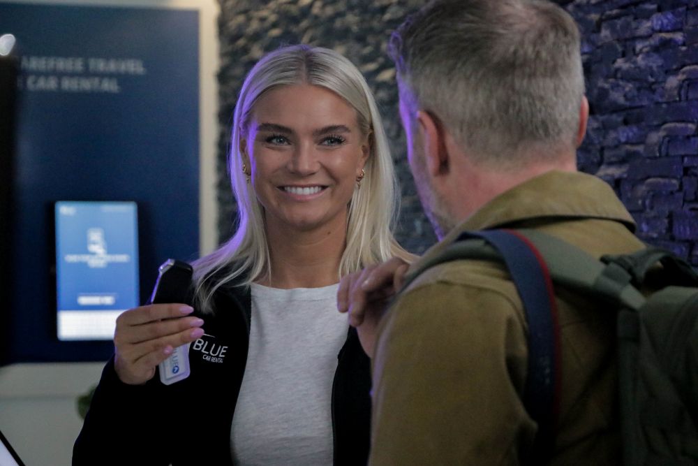 Blue Car Rental staff handing over the key to the rental car in Iceland.