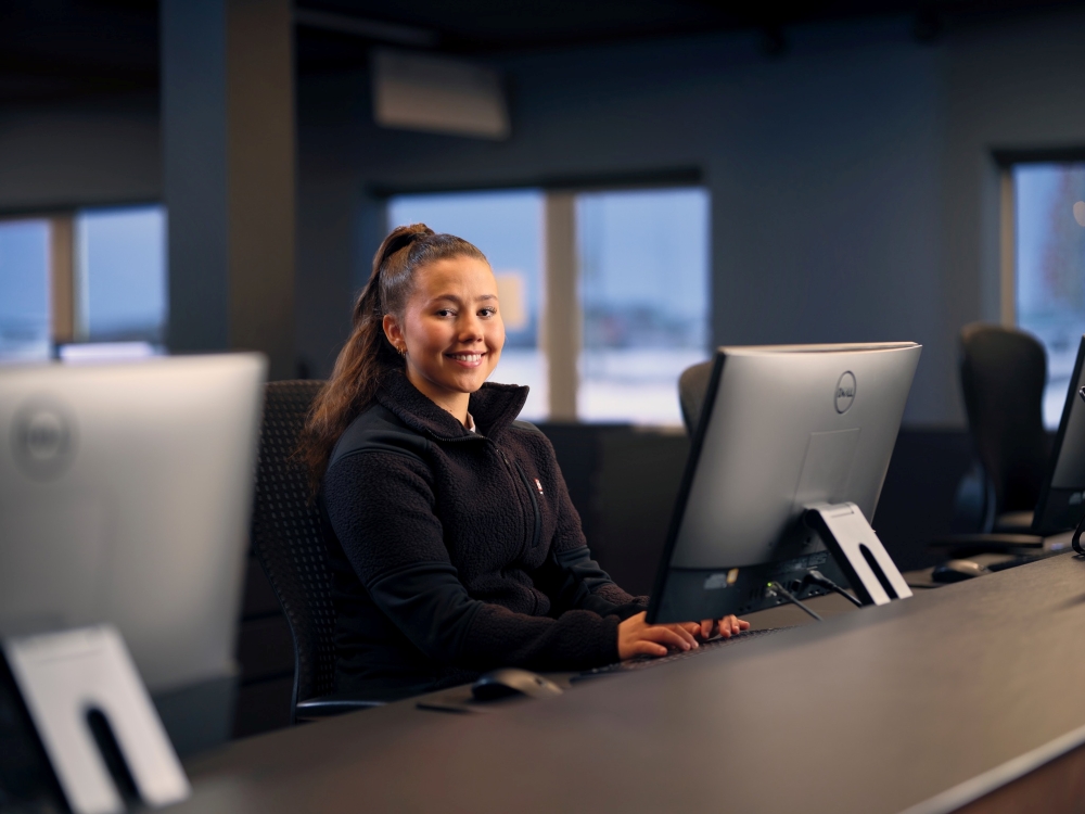 Blue car rental staff member sitting behind the desk at Keflavik airport office.