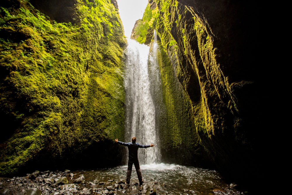 Man standing in Nauthusagil canyon and waterfall in Icealnd.
