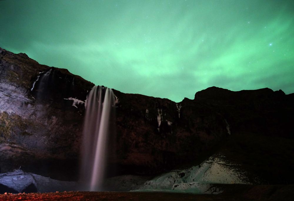 Seljalandsfoss waterfall. Northern lights over Seljalandsfoss waterfall.