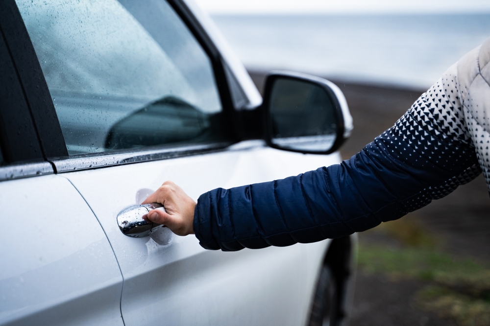Customer reaching for the handle on a car door in Iecland.