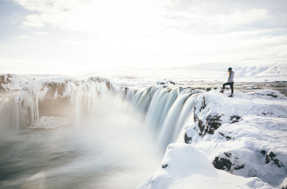 Man standing on the edge of a frozen waterfall in Iceland.